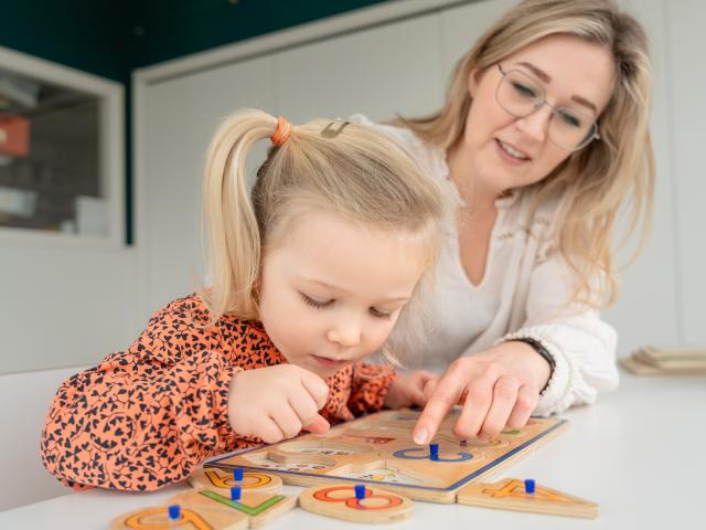 pedagogisch medewerker helpt kind met puzzel