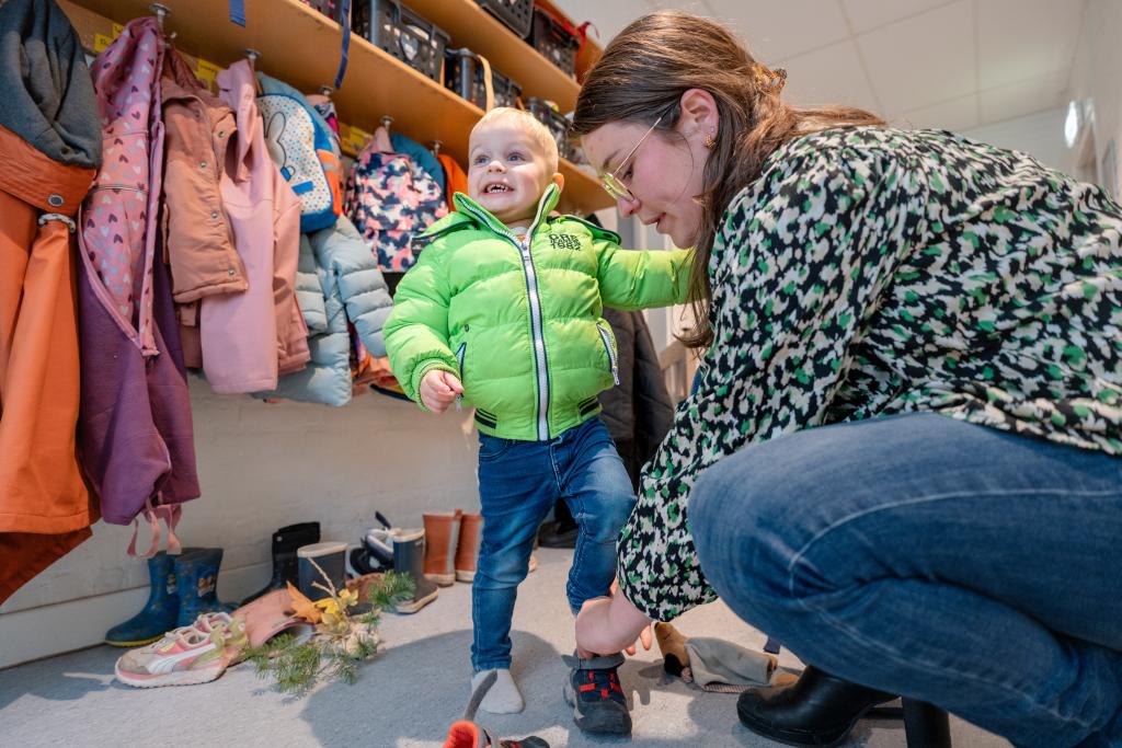 Pedagogisch medewerker doet kind schoenen aan