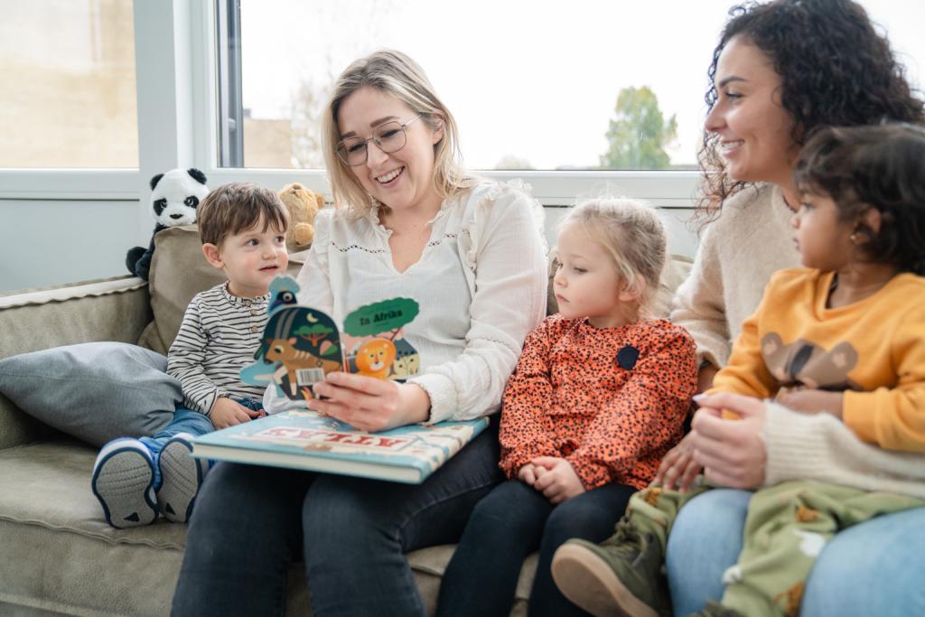Kinderen lezen samen met pedagogisch medewerkers een boek